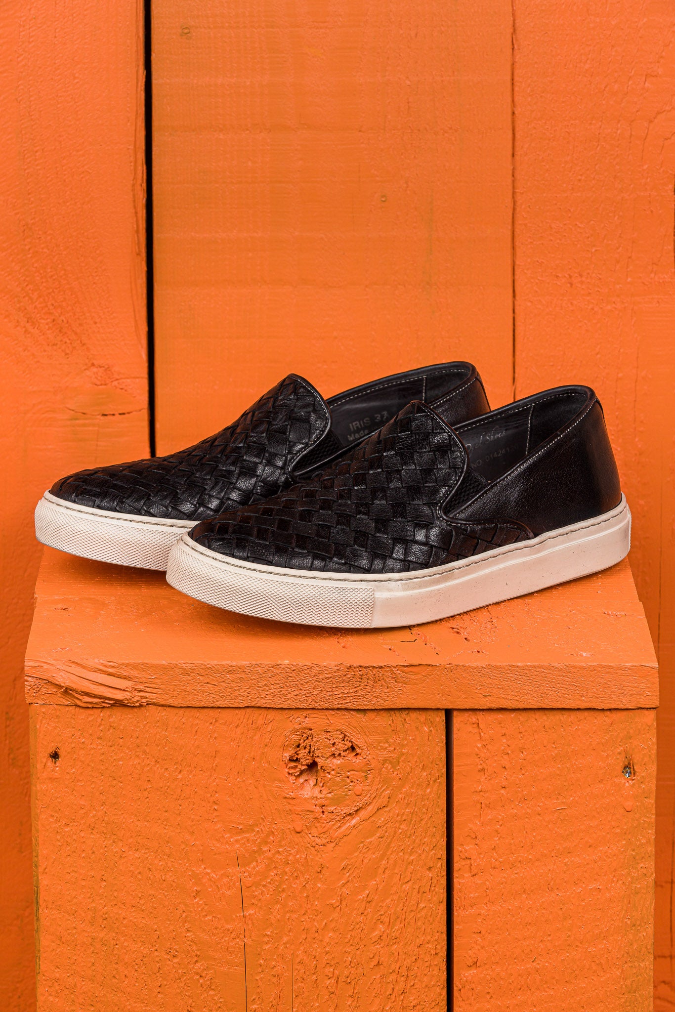 Front angled view of Iris unisex woven slip-on shoes in black leather with white rubber soles.