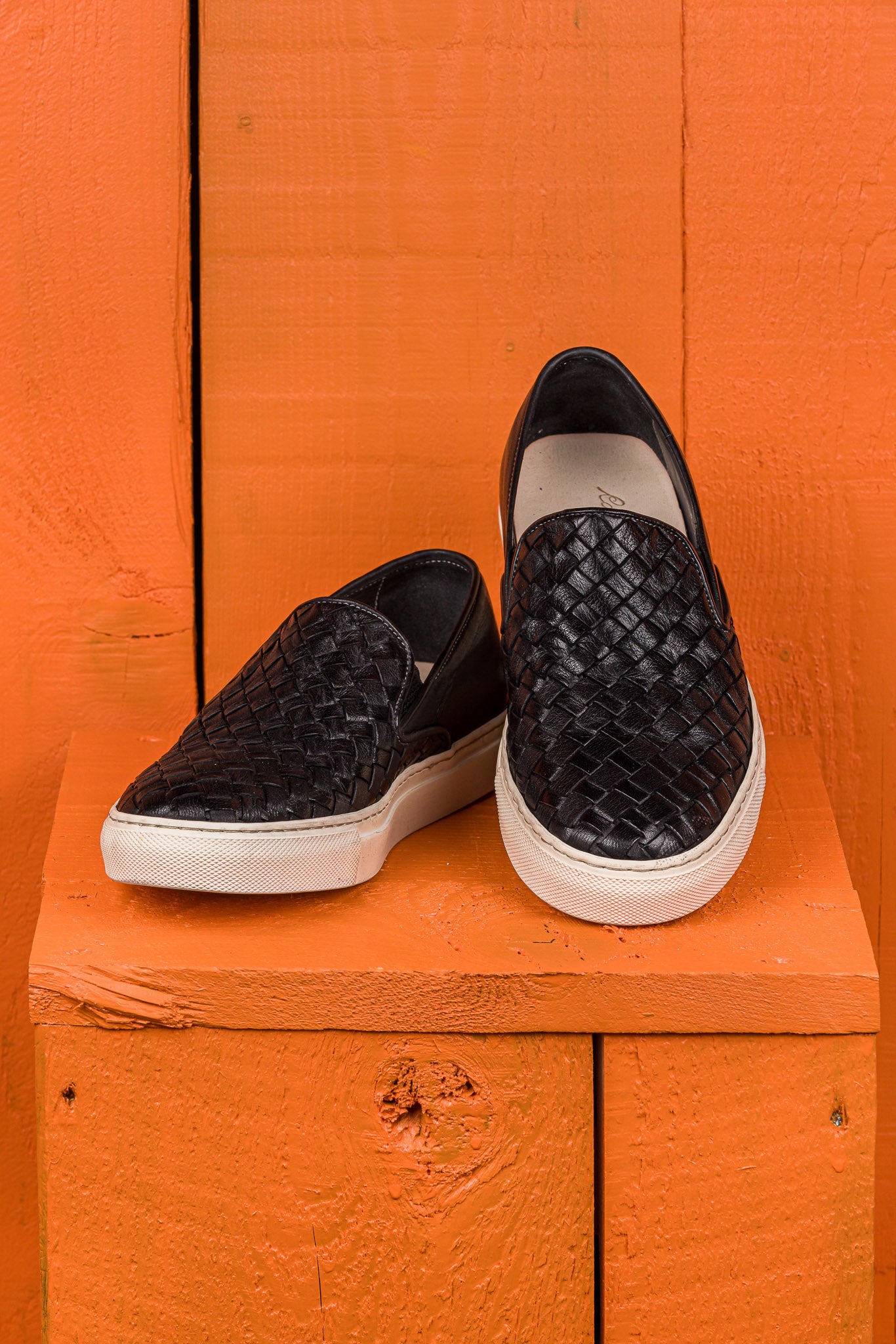Front angled and top view of Iris unisex woven slip-on shoes in black leather with white rubber soles.
