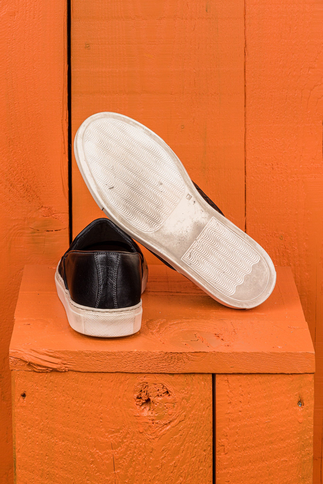 Rear view of Benheart Iris woven black leather slip-on shoes, one showing the heel and the other the rubber sole.