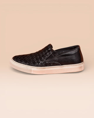 Side view of Iris unisex woven slip-on shoes in black leather with white rubber soles.