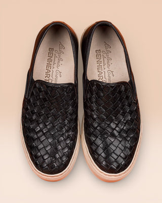 Top view of Iris unisex woven slip-on shoes in black leather with white rubber soles.