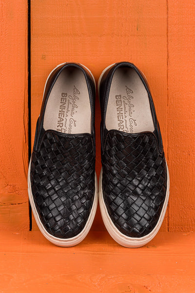 Top view of Iris unisex woven slip-on shoes in black leather with white rubber soles.