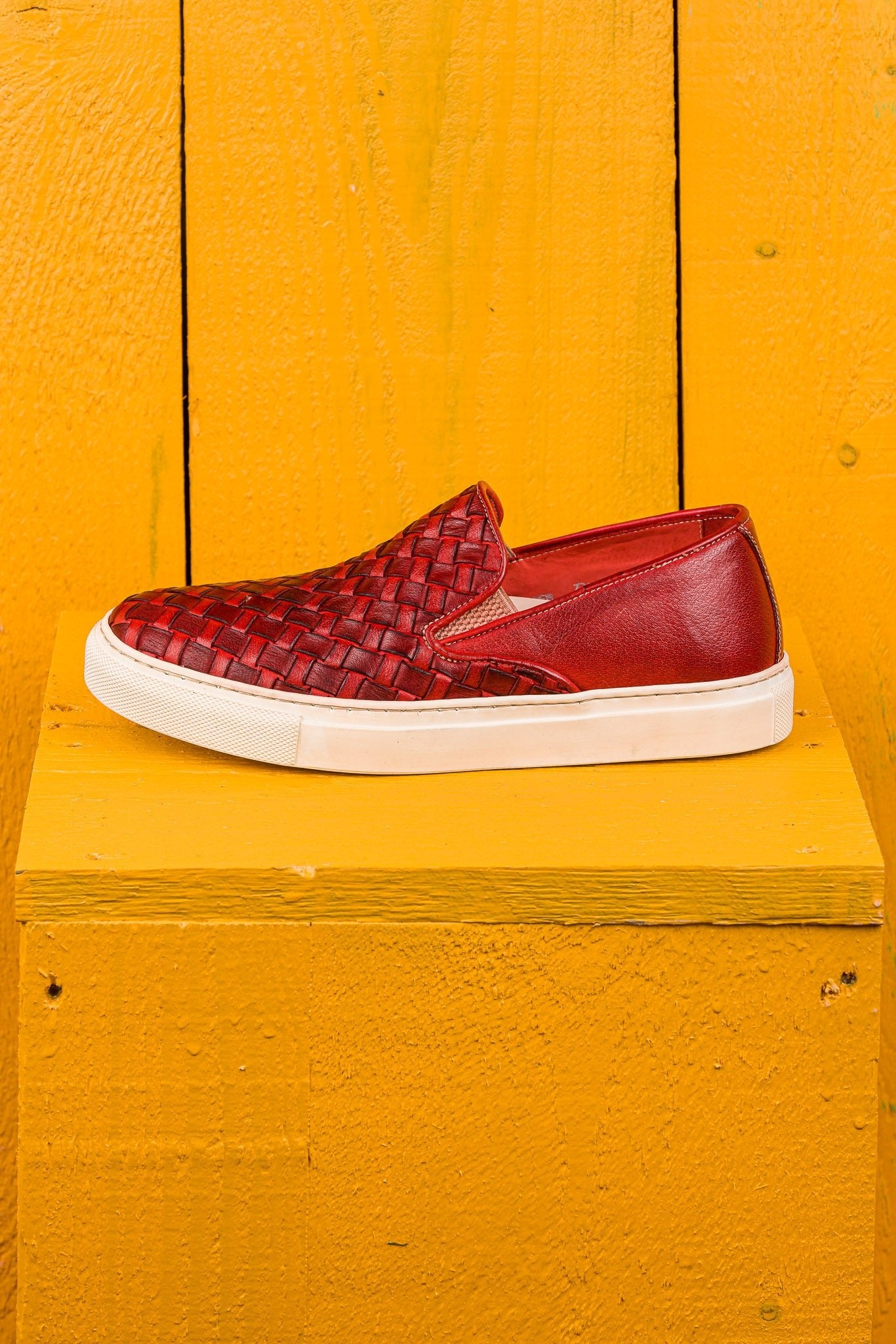 Side view of Iris unisex woven slip-on shoes in porpora leather with white rubber soles.