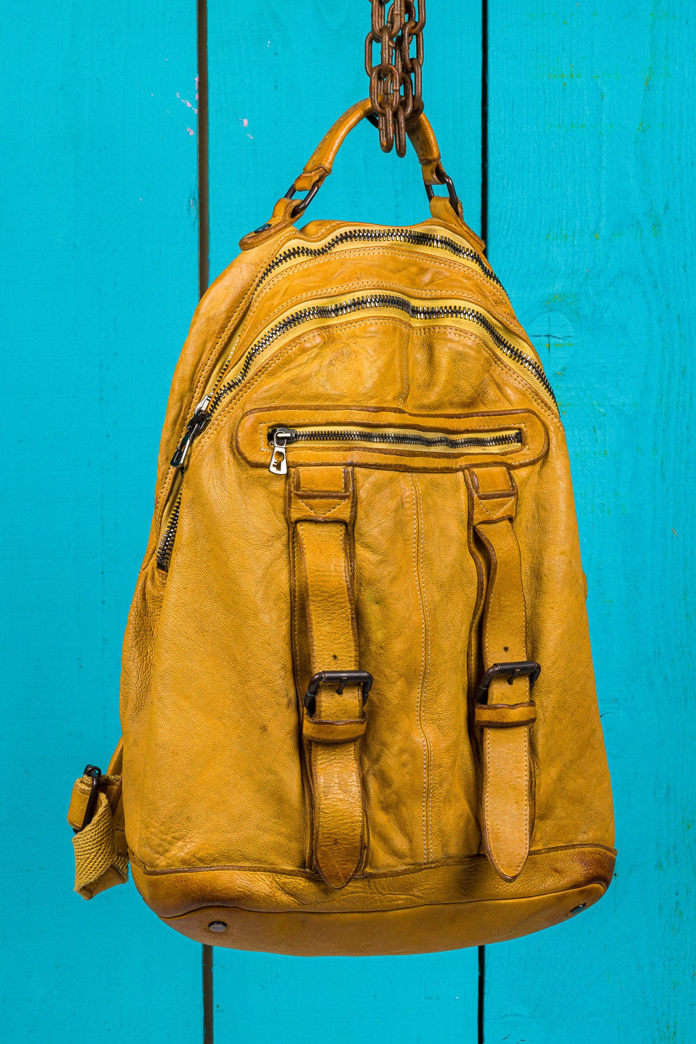 Three-quarter view of the Lorenzo unisex leather backpack in mahogany, showing front pockets and zipper details.