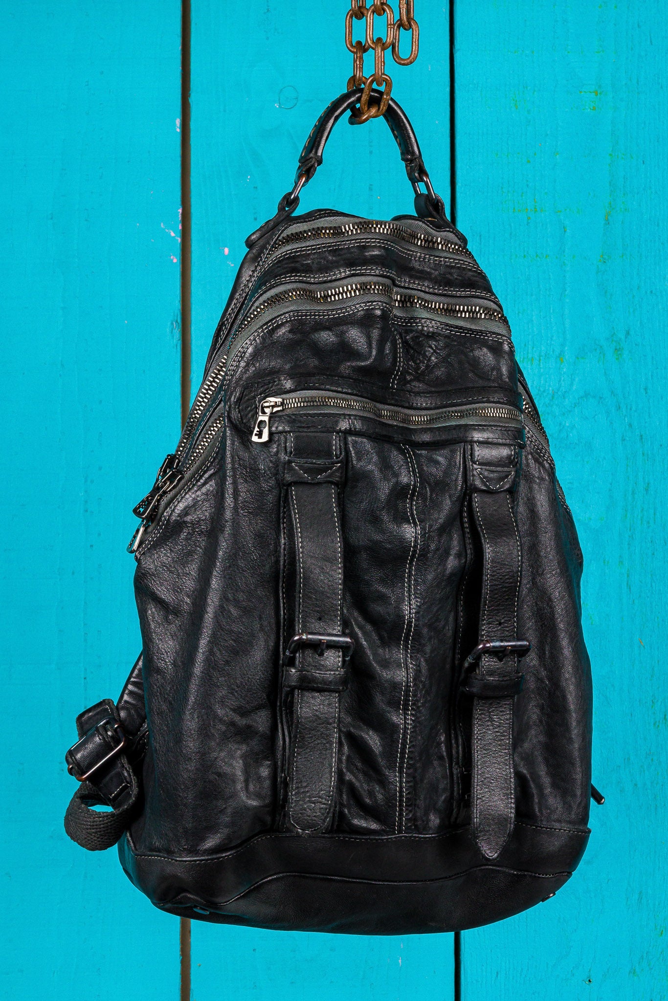 Three-quarter view of the Lorenzo unisex leather backpack in black, showing front pockets and zipper details.